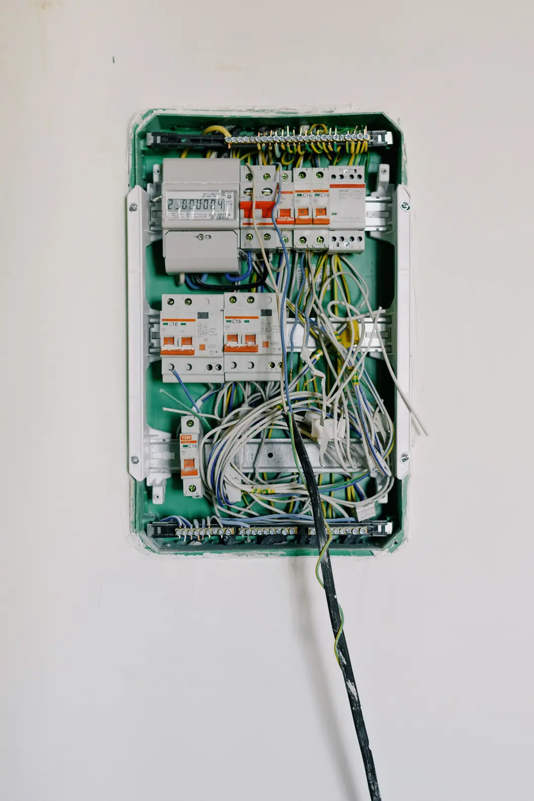 Tableau électrique ouvert en cours de câblage, avec compteur, disjoncteurs et faisceaux de fils apparents